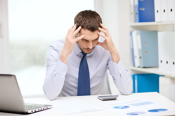 Image showing stressed businessman with laptop and documents