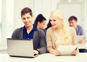 Image showing two smiling students with laptop and tablet pc