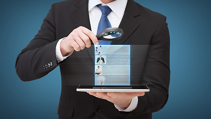 Image showing businessman hand holding magnifier over tablet pc