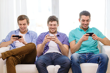 Image showing smiling friends with smartphones at home