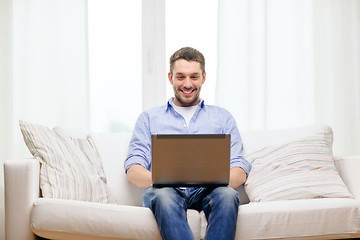 Image showing smiling man working with laptop at home