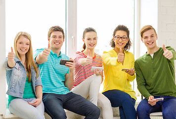 Image showing smiling students with smartphone texting at school