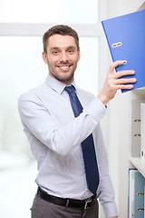 Image showing handsome businessman picking folder at office