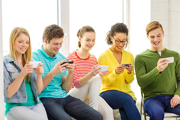 Image showing smiling students with smartphone texting at school