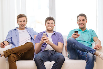 Image showing smiling friends with smartphones at home
