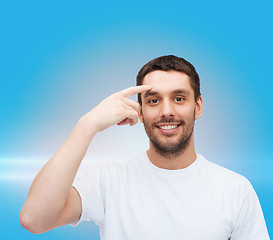 Image showing smiling young handsome man pointing to forehead