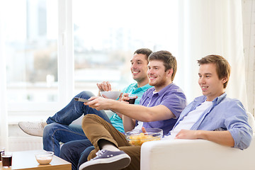 Image showing smiling friends with remote control at home