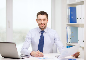 Image showing smiling businessman with laptop and documents