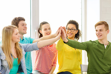 Image showing smiling students making high five gesture sitting