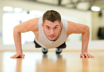 Image showing concentrated man doing push-ups in the gym