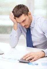 Image showing stressed businessman with laptop and documents