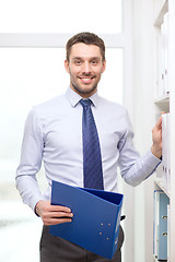 Image showing handsome businessman picking folder at office