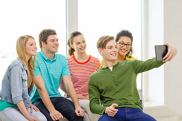 Image showing smiling students making picture with tablet pc