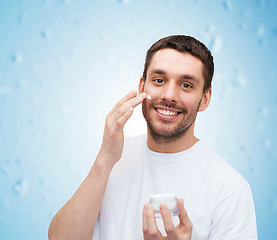 Image showing beautiful smiling man applyin cream