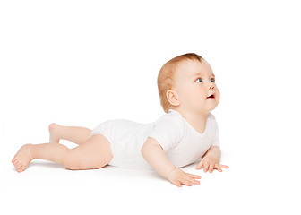 Image showing smiling baby lying on floor and looking up