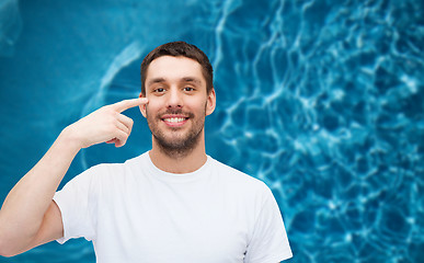 Image showing smiling young handsome man pointing to eyes