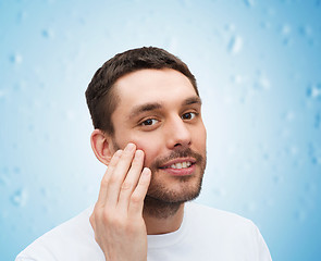 Image showing beautiful smiling man touching his face