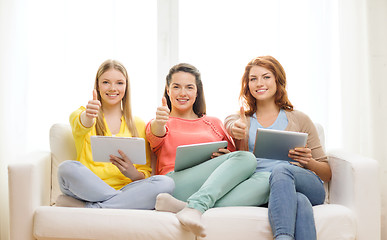 Image showing three smiling teenage girls with tablet pc at home