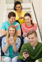 Image showing smiling students with smartphone texting at school