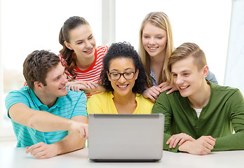 Image showing smiling students looking at laptop at school