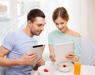 Image showing smiling couple with tablet pc reading news