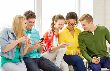 Image showing smiling students with smartphone texting at school