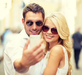 Image showing smiling couple with smartphone in the city