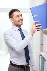 Image showing handsome businessman picking folder at office