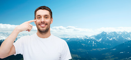 Image showing smiling young handsome man pointing to eyes