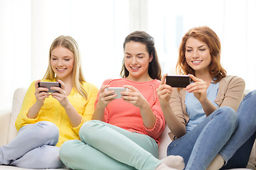 Image showing smiling teenage girls with smartphones at home