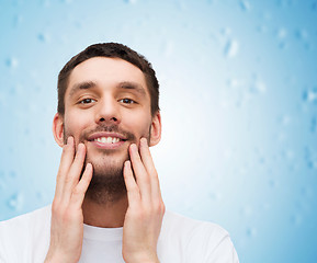 Image showing beautiful smiling man touching his face