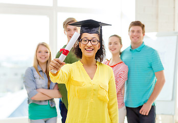 Image showing smiling female student with diploma and corner-cap