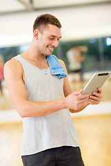 Image showing young man with tablet pc computer and towel in gym