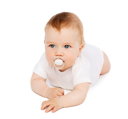 Image showing smiling baby lying on floor with dummy in mouth