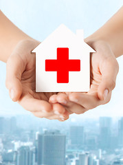 Image showing hands holding paper house with red cross