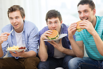 Image showing smiling friends with soda and hamburgers at home
