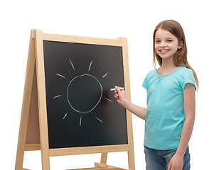 Image showing happy little girl with sun drawn on blackboard