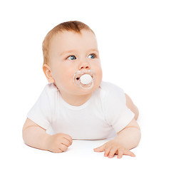 Image showing smiling baby lying on floor with dummy in mouth