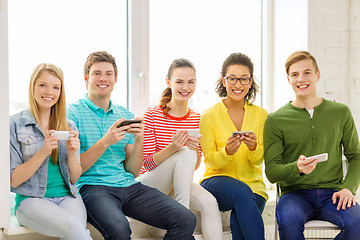 Image showing smiling students with smartphone texting at school