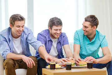 Image showing smiling friends with soda and hamburgers at home