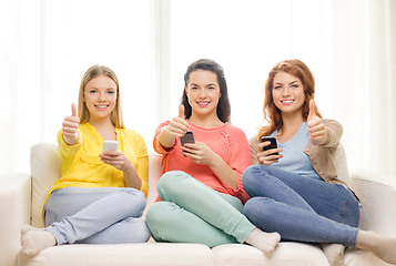 Image showing smiling teenage girls with smartphones at home