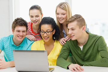 Image showing smiling students looking at laptop at school