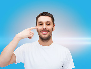 Image showing smiling young handsome man pointing to eyes