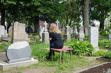 Image showing Sorrow woman shrinked near father husband tomb 