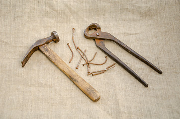 Image showing hammer with nail and pliers lying on linen texture 