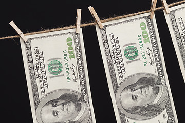 Image showing Hundred Dollar Bills Hanging From Clothesline on Dark Background