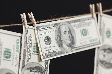 Image showing Hundred Dollar Bills Hanging From Clothesline on Dark Background