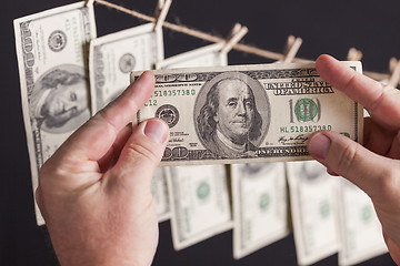 Image showing Male Holding Hundred Dollar Bills, Many Handing from Clothesline