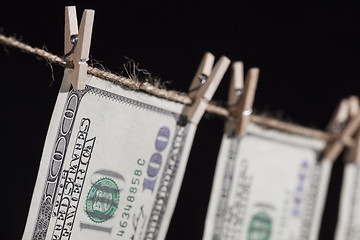 Image showing Hundred Dollar Bills Hanging From Clothesline on Dark Background