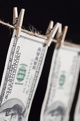 Image showing Hundred Dollar Bills Hanging From Clothesline on Dark Background